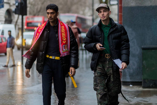A model wearing a vintage football jersey paired with an oversized jacket and sneakers, blending retro football and streetwear fashion.